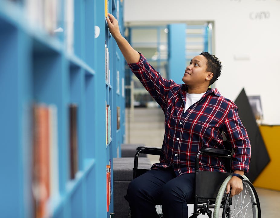 Man in wheelchair reaching to get library book