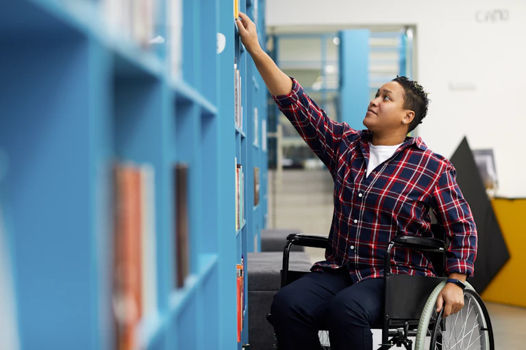 Man in wheelchair reaching to get library book