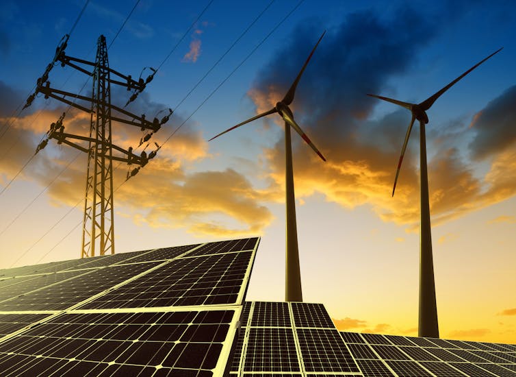 A concept image of solar panels with two wind turbines and a pylon looming over them.