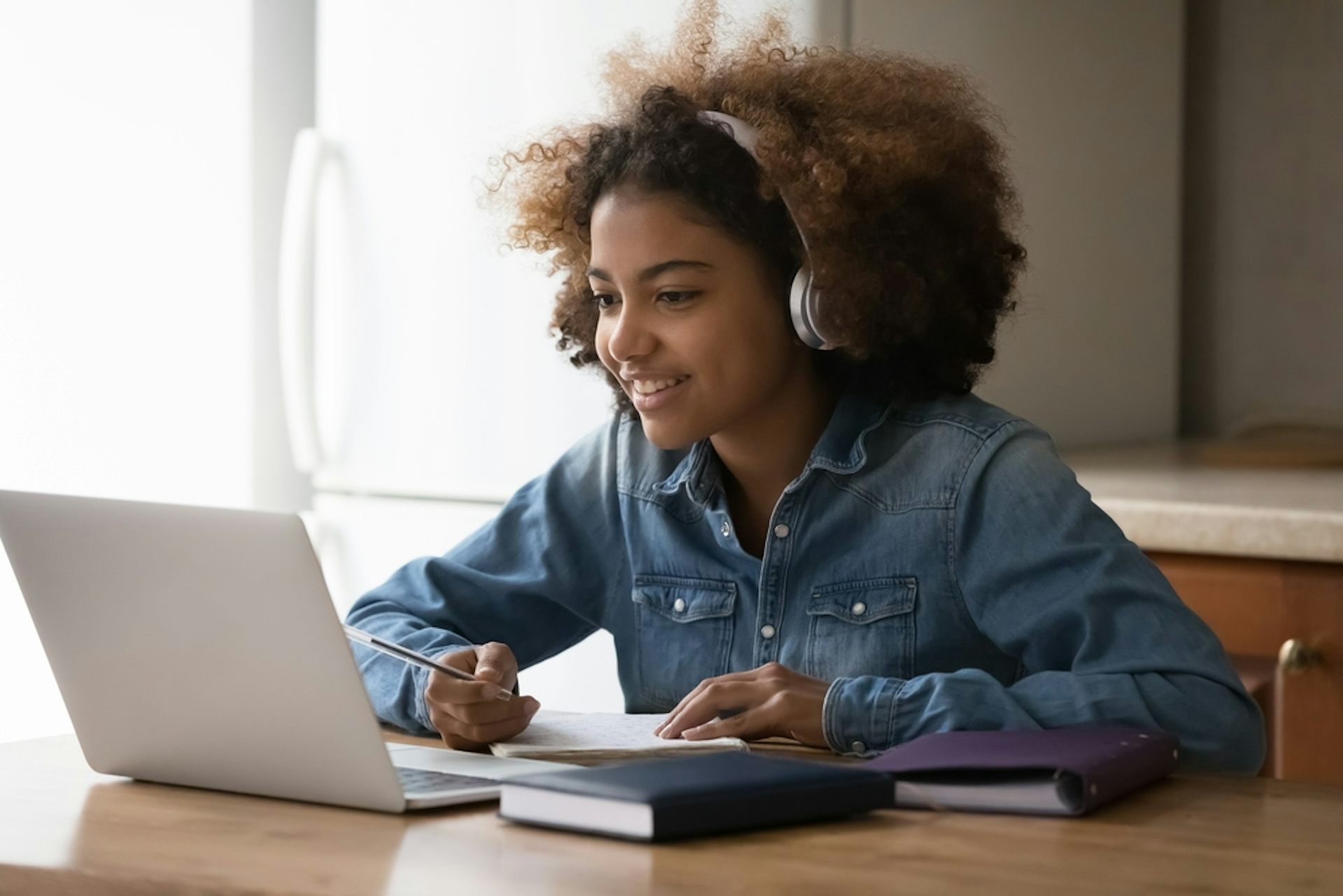 Une adolescente discutant en ligne avec un professeur, utilisant des écouteurs et un ordinateur portable