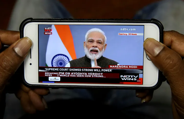 Mobile phone screen showing Narendra Modi speaking on news programme.