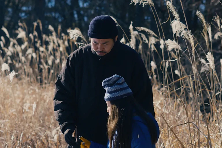 Takumi and his daughter in a field.