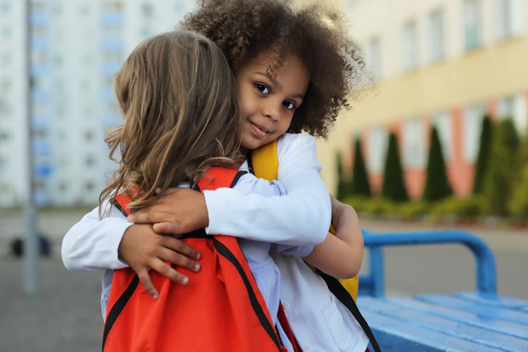 Two young girls embrace at a school playground