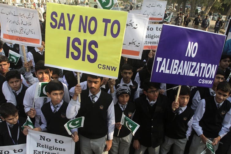 Students carry signs that read Say No to ISIS and No Talibanization.