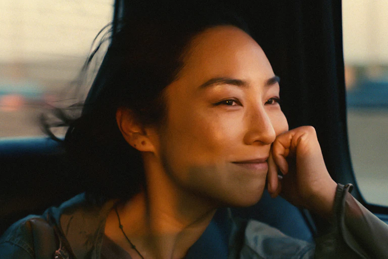A woman's smiling and wistful face seen illuminated by warm light