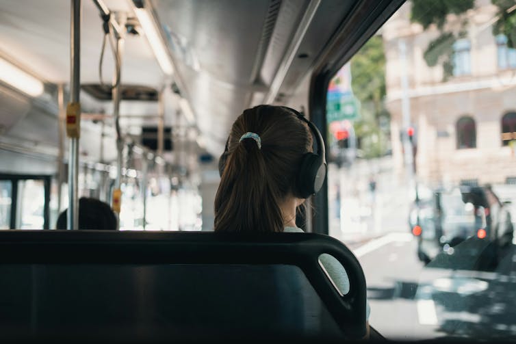 A girl with headphones on a bus.