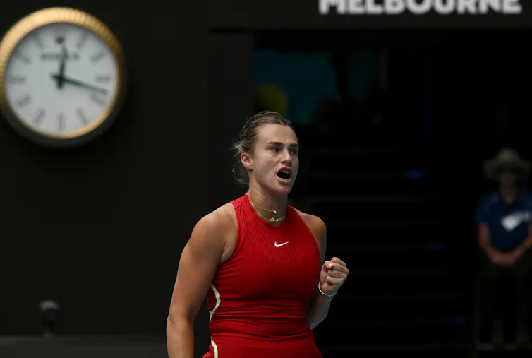 A woman in red Nike singlet with clock behind her showing twenty past midnight