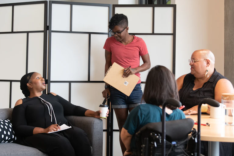 a group of women talk inside. some have visible disability