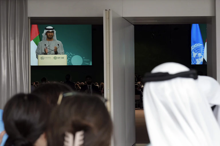 People watch COP28 President Sultan al-Jaber on a screen as he speaks during a plenary session at the COP28 U.N. Climate Summit, Wednesday, Dec. 13, 2023, in Dubai, United Arab Emirates.