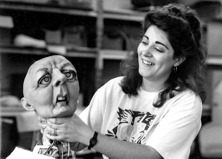 A member of the Spitting Image team pretends to throttle the famous puppet head of Margaret Thatcher.