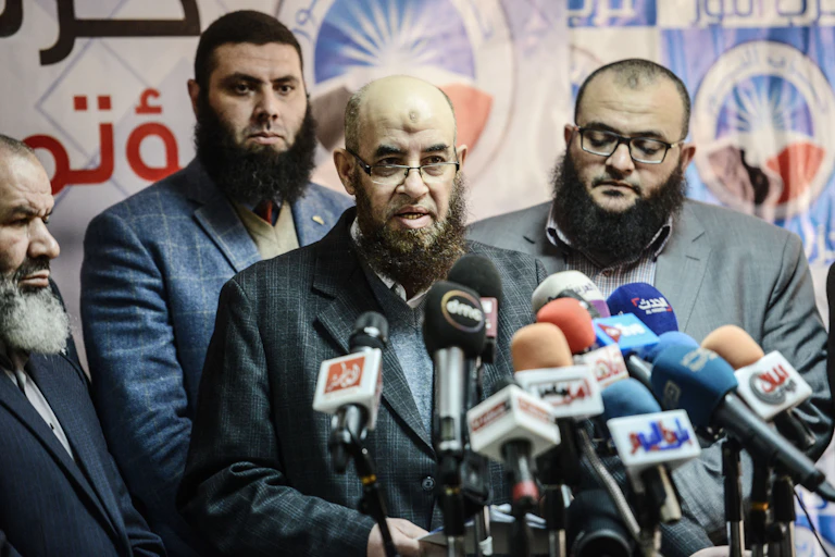 Quatre hommes barbus s'expriment devant des micros