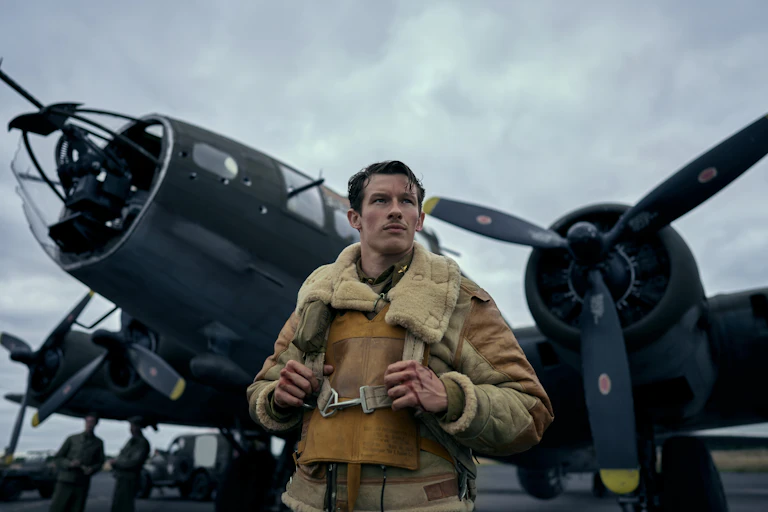 Airforce pilot stood in front of a bomber plane.