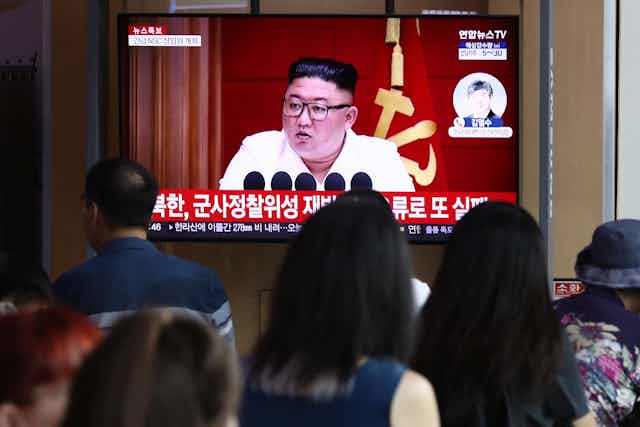 A TV screen shows a man in glasses over a Korean caption.