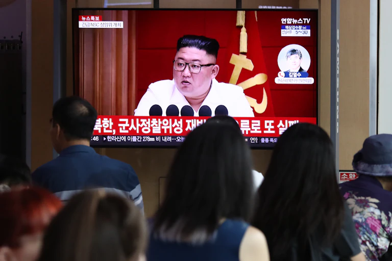 A TV screen shows a man in glasses over a Korean caption.