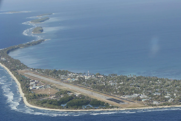 An aerial photo of a narrow tropical atoll