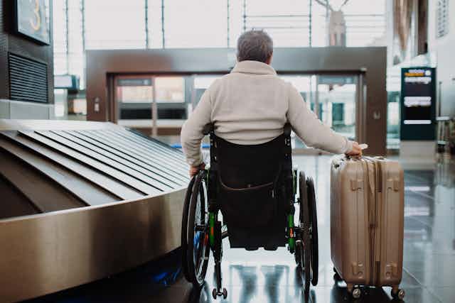 man in wheelchair with luggage at airport terminal