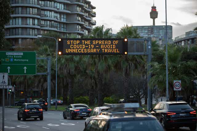 A sign in Sydney advising avoiding unnecessary travel to stop COVID spread.