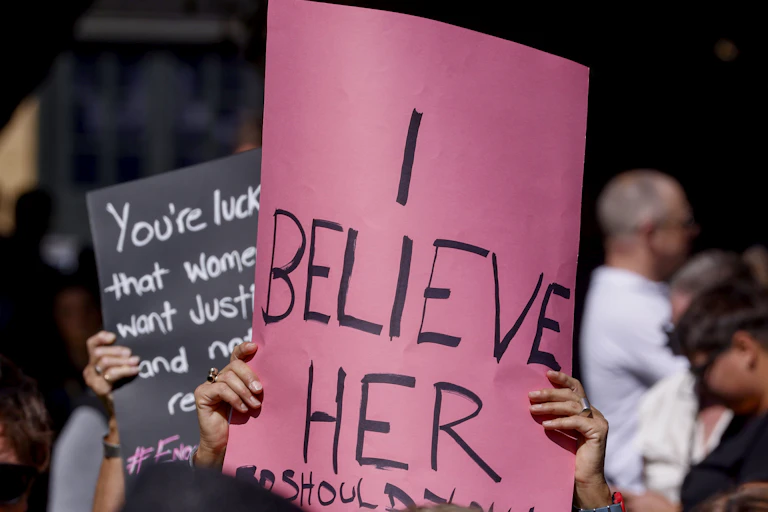 A pink sign that reads 'I believe her'