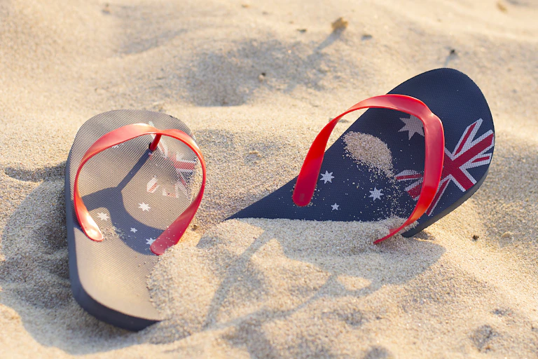 Thongs decorated with the Australian flag lying on a beach