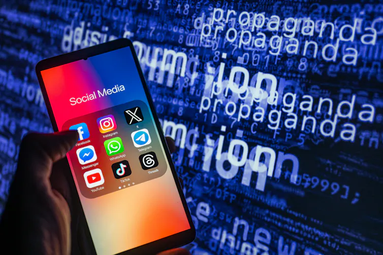 Social media icons logo displayed on a smartphone with disinformation on screen seen in the background, in this photo illustration.