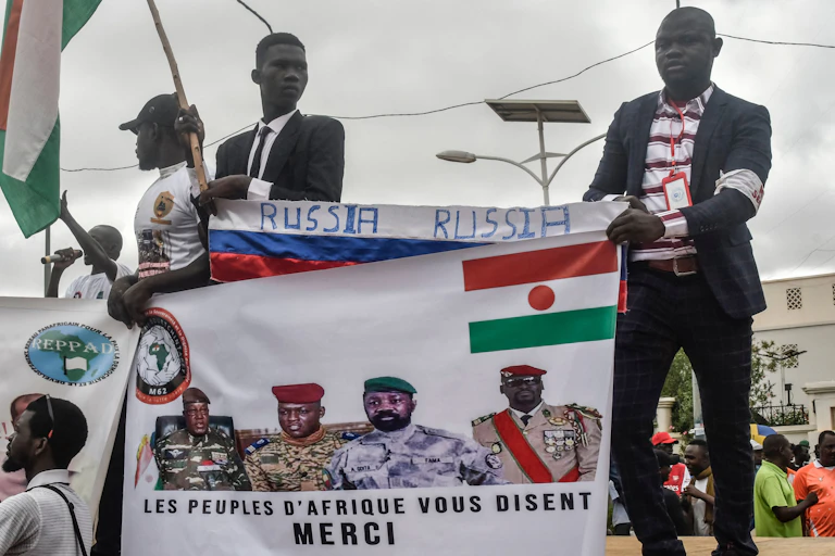 Men holding a banner depicting men in military uniforms.