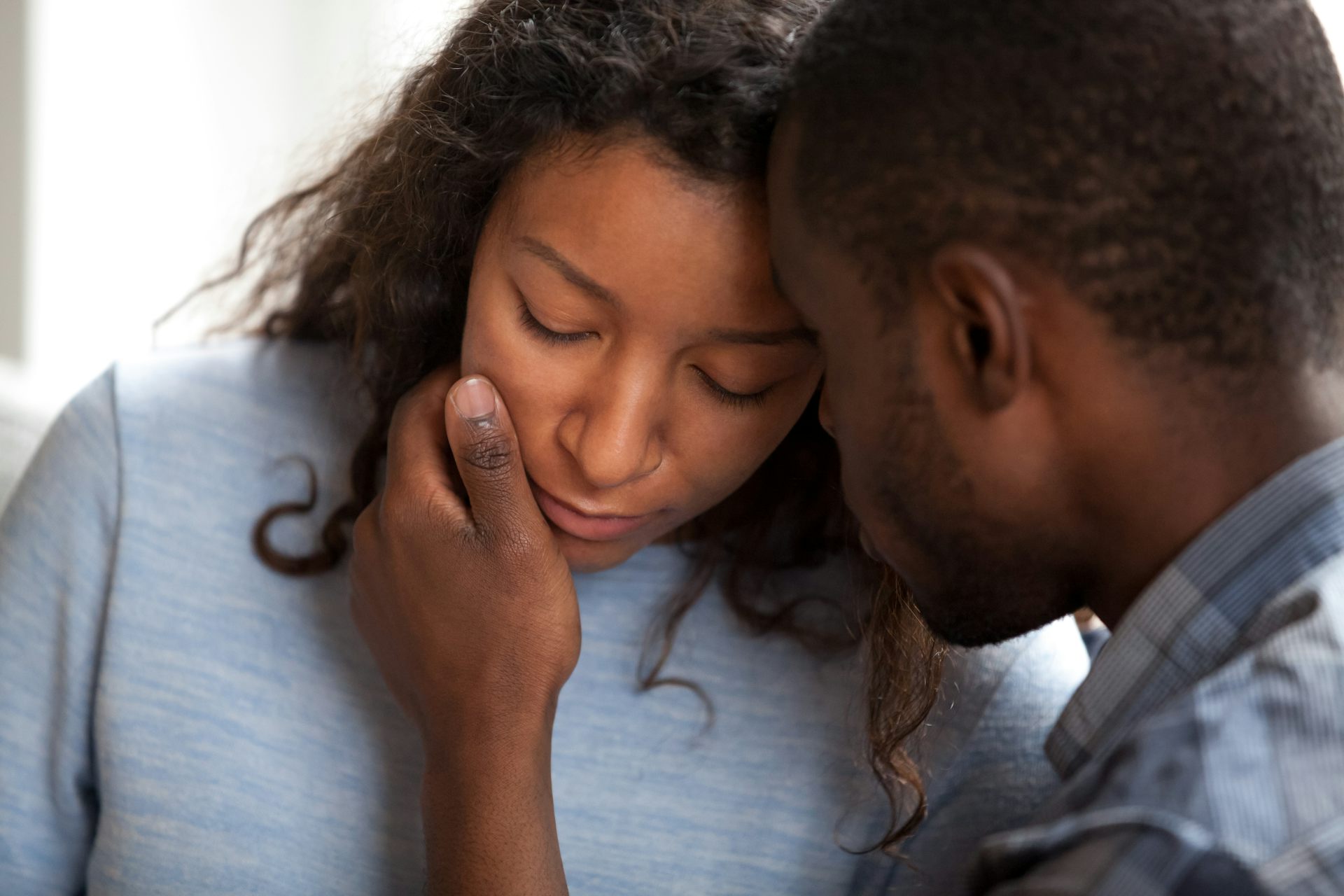 Un homme réconforte une femme en lui caressant la joue