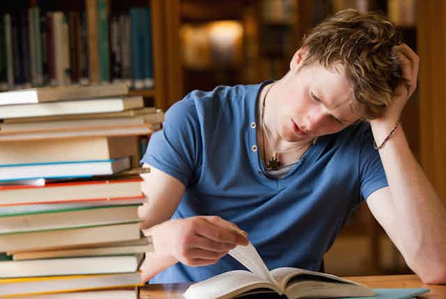 Um jovem lendo um livro numa biblioteca