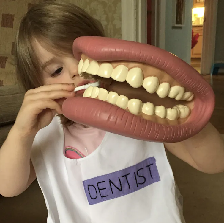 Girl brushes giant model teeth