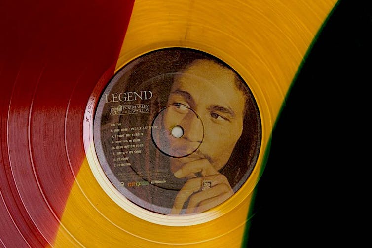 Un disco rojo, amarillo y verde con la cara de un hombre contemplativo con rastas.