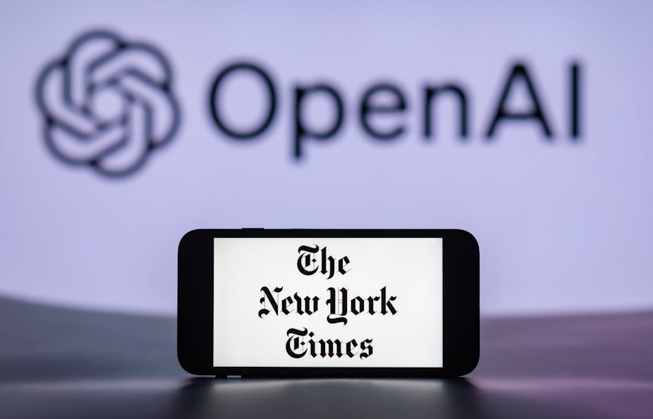 In a photo illustration, a mobile phone displays the logo of The New York Times, with that of OpenAI in the background.
