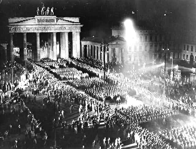 Troops with torches march in front of the Brandenburg Gate