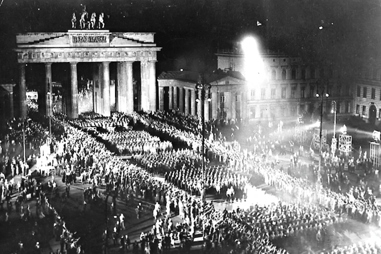 Troops with torches march in front of the Brandenburg Gate