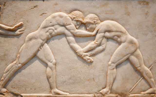 A carving of two men wrestling on a piece of white stone