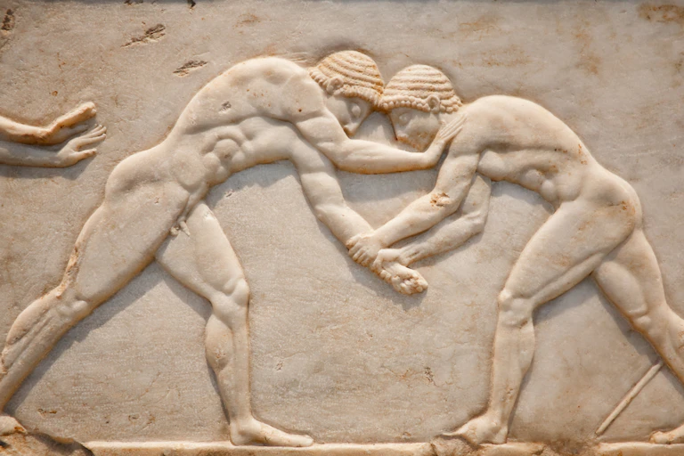 A carving of two men wrestling on a piece of white stone