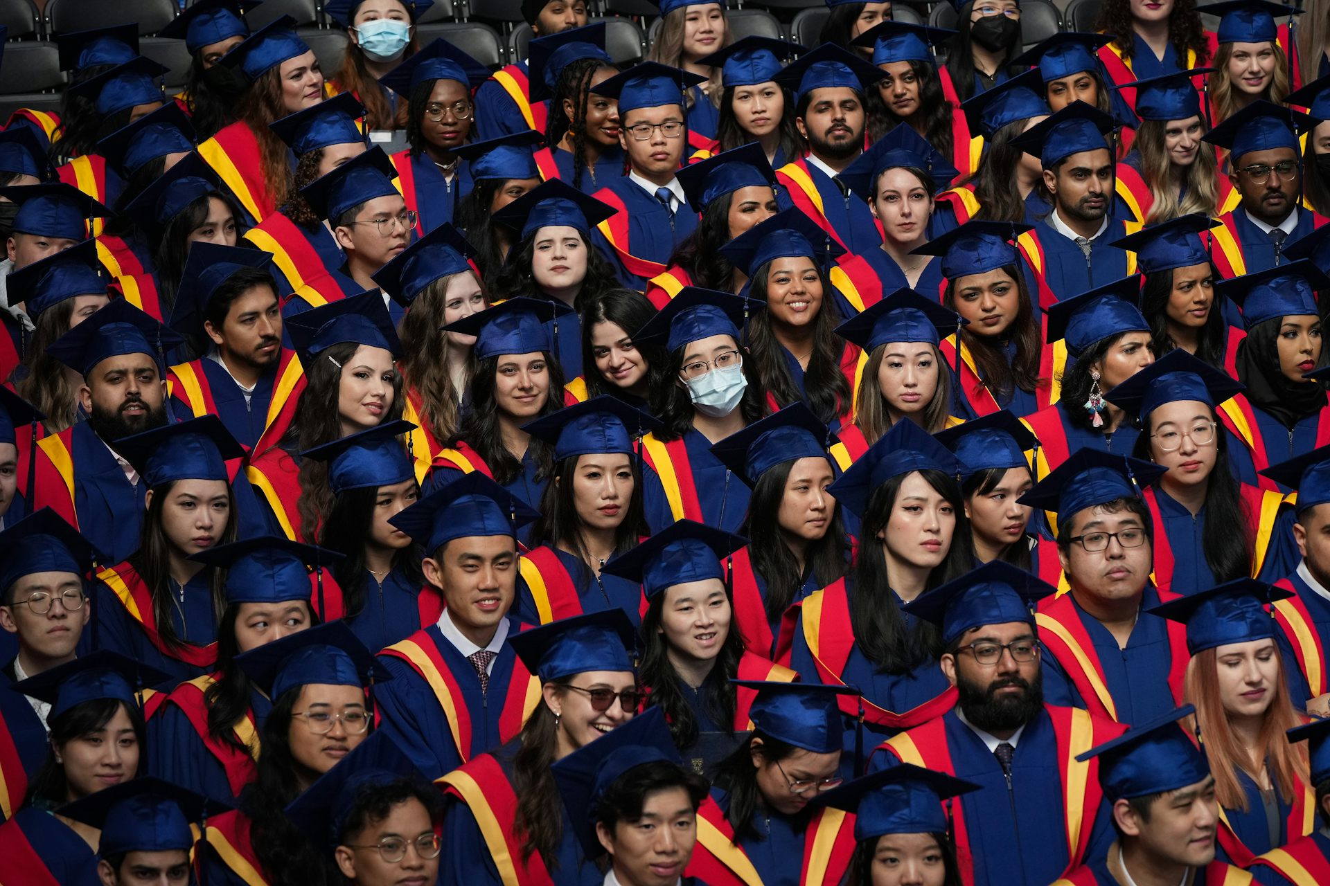 Graduating students in gowns and caps in an event hall.
