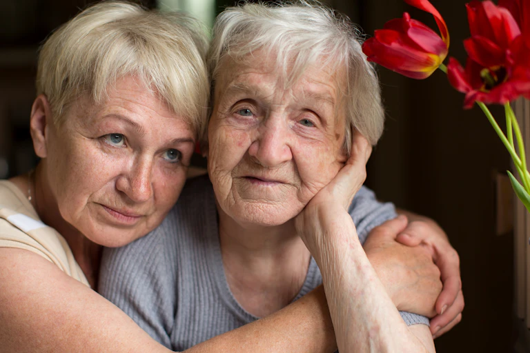 An older woman and her daughter embrace.