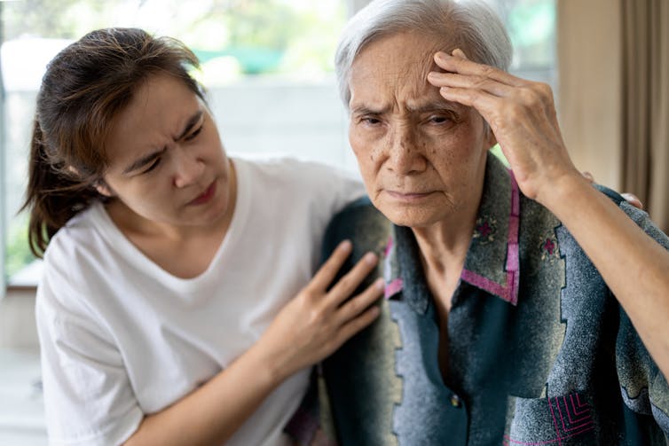 An older Asian woman sits with her daughter.