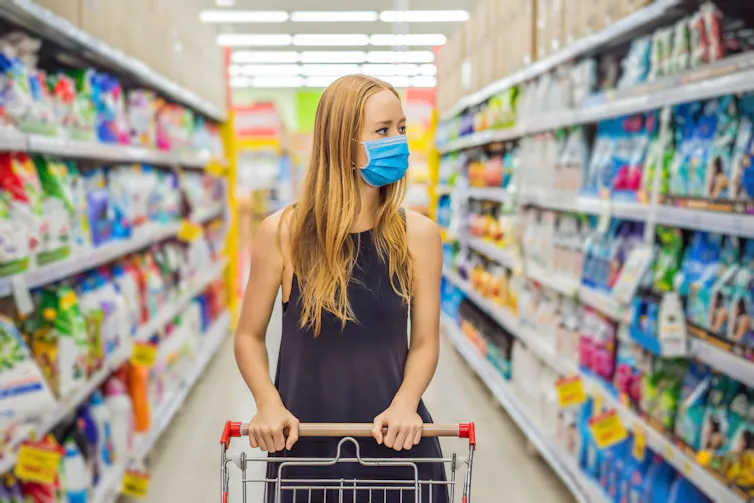 Uma mulher em um supermercado usando uma máscara.