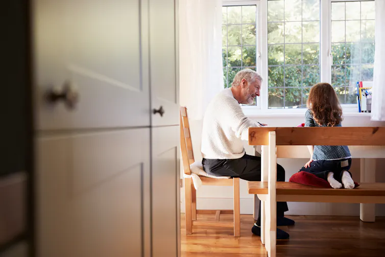 A grandfather and grandchild at a table.