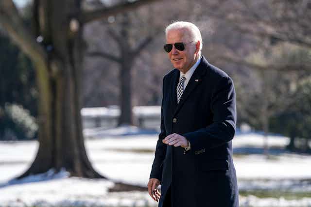 Joe Biden wearing sunglasses and an overcoat.