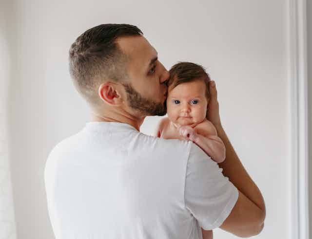 Young man kissing baby on head