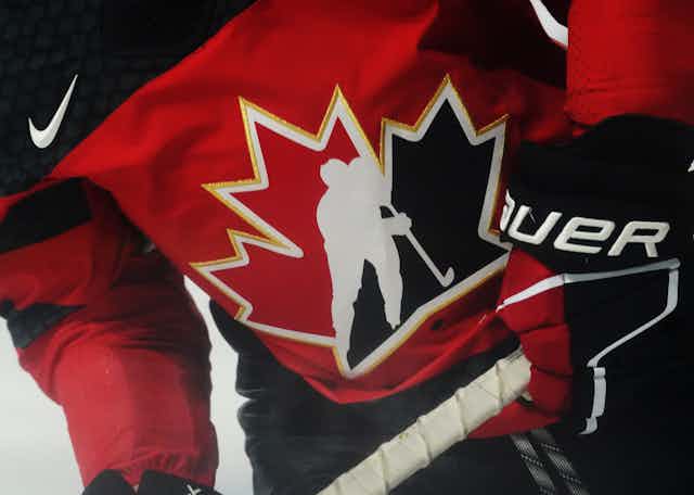 Close up of a hockey jersey that has a black and red Canadian flag on it with the silhouette of a hockey player in front
