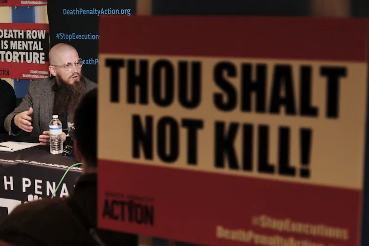 An anti-death penalty campaigner protests against the death penalty with a poster reading 'Thou shalt not kill'.