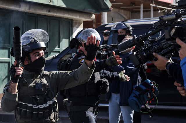 Des militaires armés et en uniforme face à des journalistes qui les filment