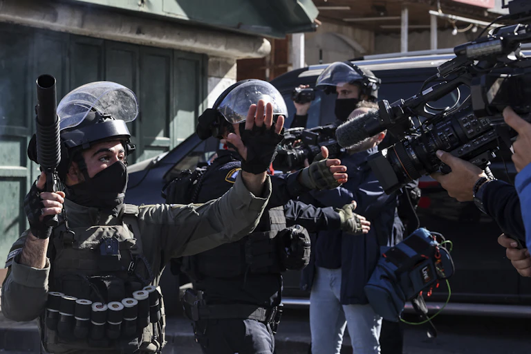 Des militaires armés et en uniforme face à des journalistes qui les filment