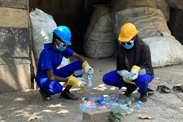 Two women burning plastic bottles.