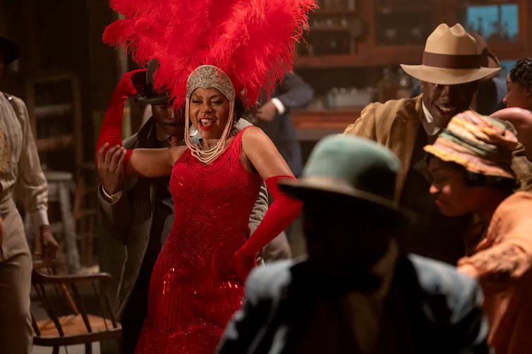 Taraji P. Henson as Shug Avery wearing a red dress and a feathered hat