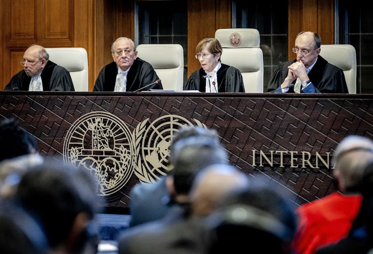 Four judges in black robes sit in a row at a desk.
