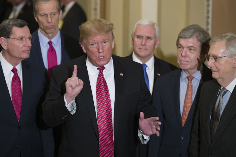 Six white men in coats and ties stand closely bunched together.