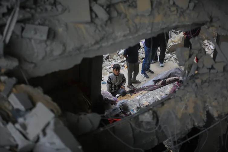 A small boy looks at a building ruined by Israeli bombing.